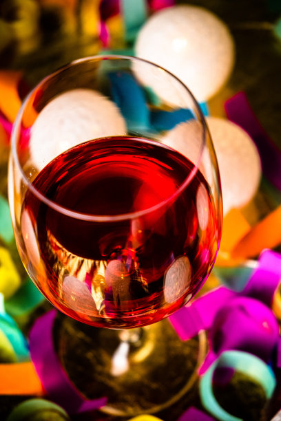 一杯红酒，花环灯和五彩纸屑。派对时间。庆祝活动的概念。图片下载
