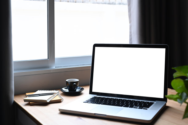 笔记本电脑，咖啡杯和木桌子上的室内植物。空白显示用于图形显示蒙太奇。图片下载