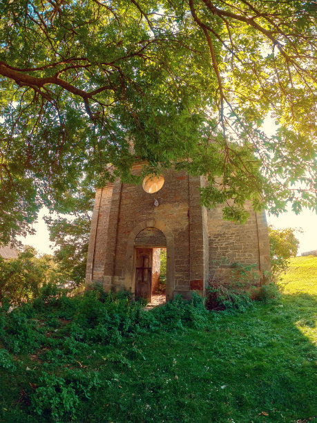 一棵大树下的中世纪废墟城堡。砖石墙，木门。古老的建筑。图片下载