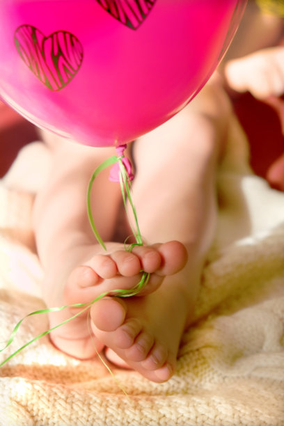 赤足和粉红色气球心形图案接近。情人节，生日和聚会庆祝。图片下载