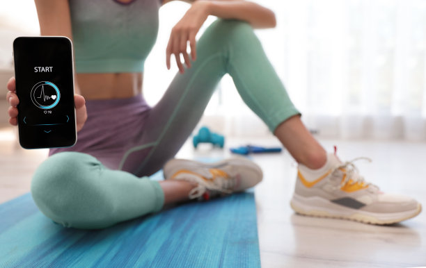 年轻女子在家里展示智能手机上的健身应用，特写图片下载