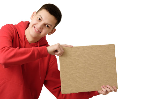快乐微笑的十几岁的男孩穿着红色连帽衫，拿着空白的棕色纸板横幅，孤立在白色的背景上。副本的空间。特写镜头。图片下载