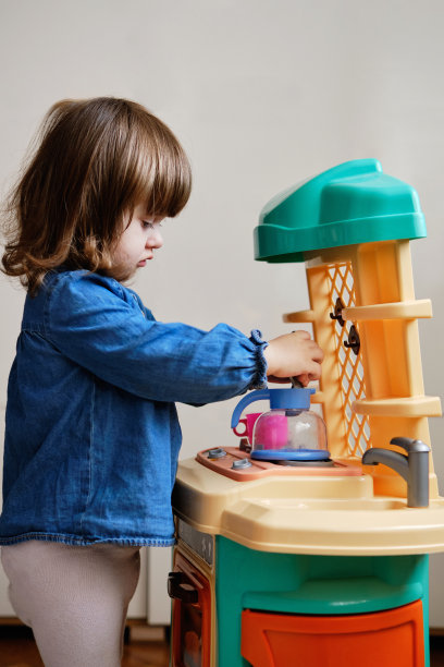 《漂亮小女孩》扮演厨师。蹒跚学步的小女孩玩玩具厨房图片下载