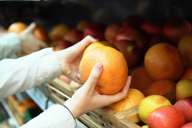 一位女士在超市挑选葡萄柚。图片下载