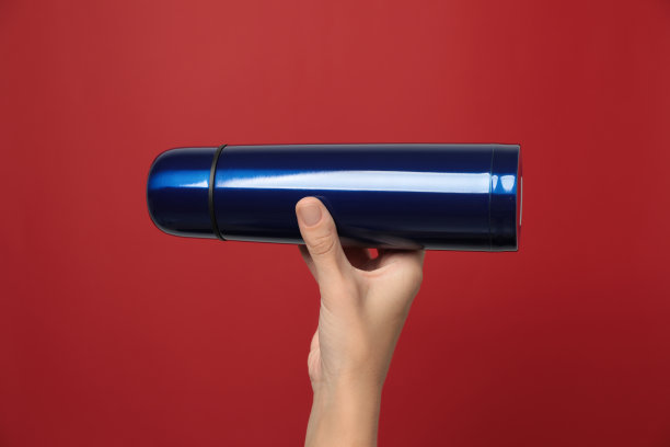 女人拿着现代的蓝色热水瓶在红色的背景上，特写图片下载