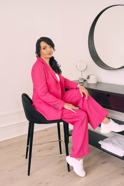 美丽，时尚，自信的黑发在现代室内的镜子在时尚的紫红色(粉红色)套装。时尚、家居、旅游、酒店理念图片下载