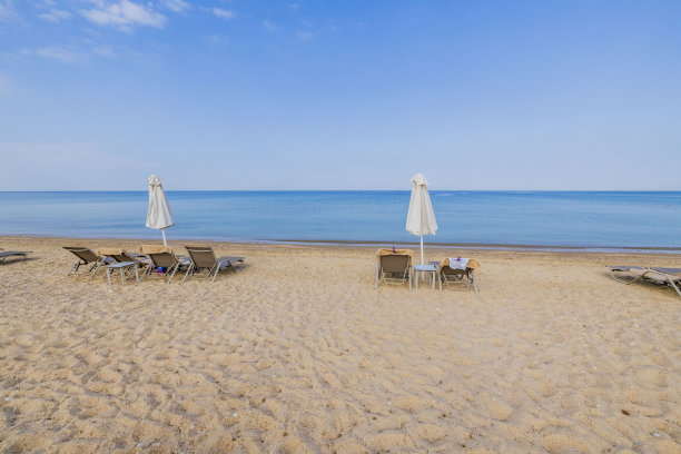在地中海的背景下，空荡荡的海滩上有太阳躺椅和雨伞，美丽的景色。希腊。图片下载