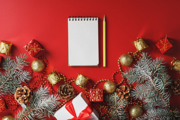 圣诞作文，用笔记本和铅笔写的愿望，圣诞树装饰在红色的背景上。图片下载