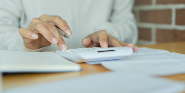接近成熟女性的手在家里用手指按在计算器上计算和总结税务的生活方式和财务概念图片下载