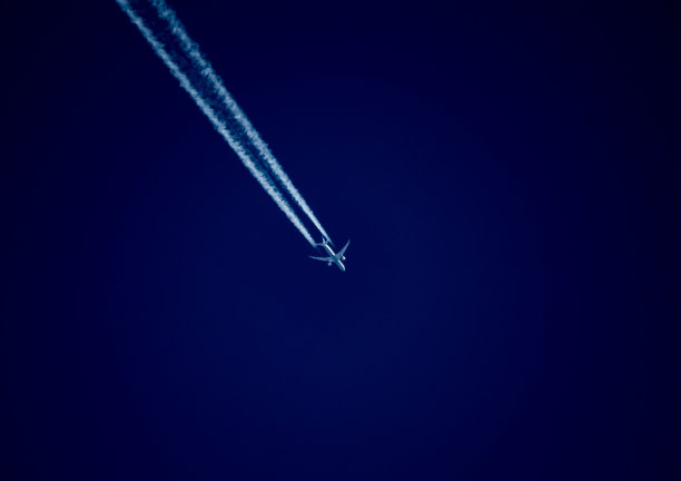 飞机在蓝天上留下一条凝结的尾迹。图片下载