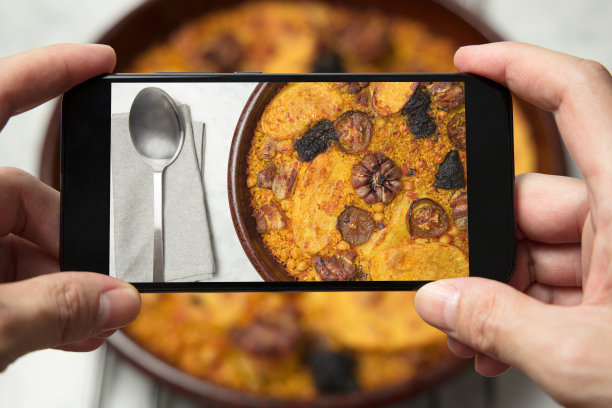 一名男子的手正在给烤好的砂锅饭拍照。瓦伦西亚,西班牙图片下载