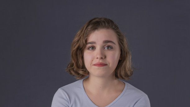 这位留着短发的年轻女子一边哭一边对着镜头摆姿势，微笑着。年轻漂亮的短发女子绝望地看着镜头，眼里噙着泪水。图片下载