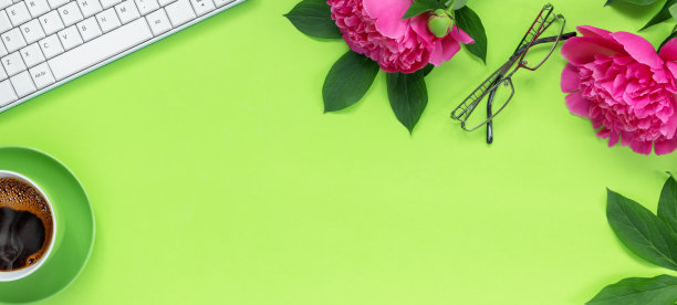 绿色办公桌上的远程家庭办公室。工作空间有键盘，笔记本，眼镜，钢笔和铅笔。一束美丽精致的粉红牡丹和一杯节日热咖啡。图片下载