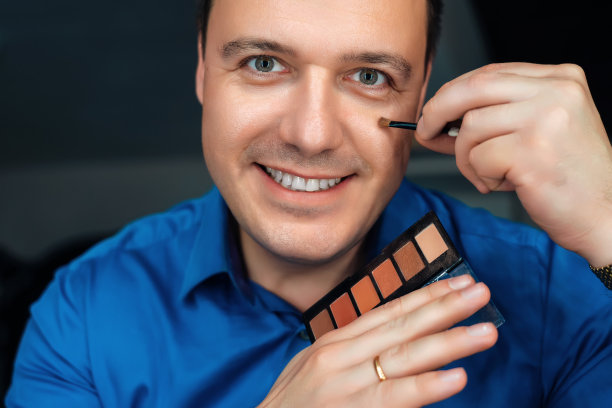 千禧一代男人在家照镜子化妆。都市美男正在用刷子往脸上抹粉。满意的帅哥喜欢早上的例行公事，个人卫生和美容程序图片下载