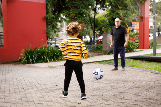 和爷爷在公园踢足球的男孩注视着前景图片下载