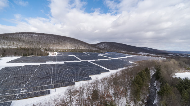 宾夕法尼亚州阿巴拉契亚山脉的大型太阳能农场，在一个阳光明媚的冬日里，一场大雪过后。图片下载