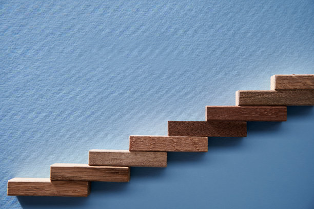 业务成长，业务成功或职业道路成功的概念。蓝色背景上，木块排列成楼梯形状。图片下载