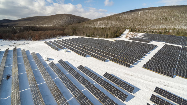 宾夕法尼亚州阿巴拉契亚山脉的大型太阳能农场，在一个阳光明媚的冬日里，一场大雪过后。图片下载