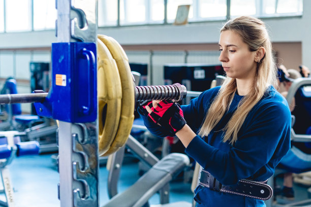 运动系列的运动员。年轻的白人女子在职业健身房，她接受了训练。穿着运动服的人像，沉重的杠铃图片下载