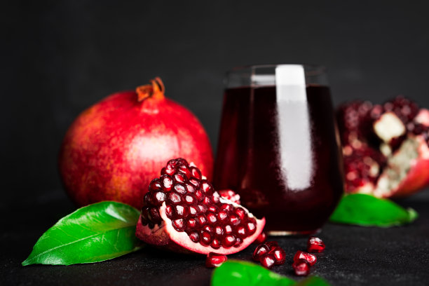 石榴和石榴籽在黑色的背景上。石榴汁图片下载