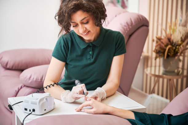 美甲师在美容院为女士做五金美甲。图片下载