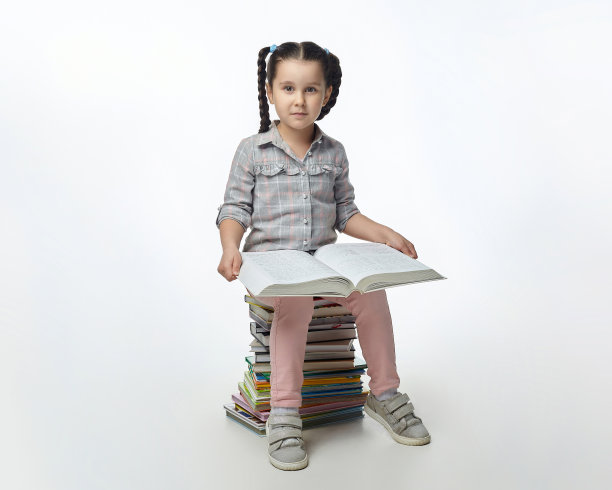 扎着辫子的可爱小女孩正坐在一大堆书上图片下载