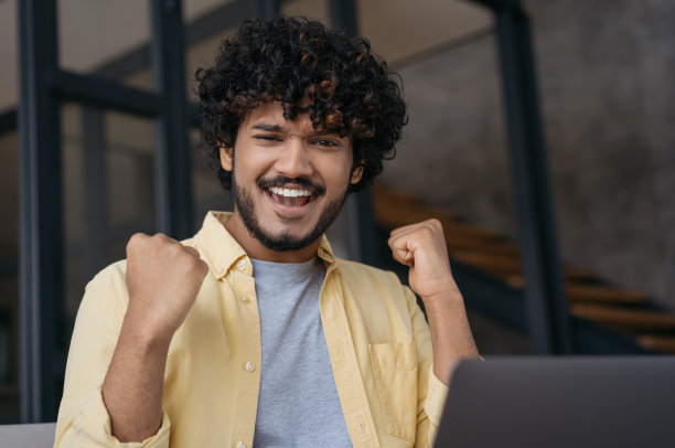 兴奋的印度学生庆祝阅读考试成绩成功。快乐的亚洲自由职业者有好消息的特写，他收到报酬图片下载