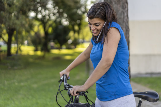 一名年轻女子的肖像，她正在推她的自行车打电话图片下载