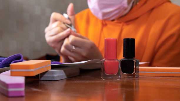 前景是锉刀和两瓶清漆。在模糊的背景中，女孩正在修指甲。图片美容网站。有选择性的重点。图片下载