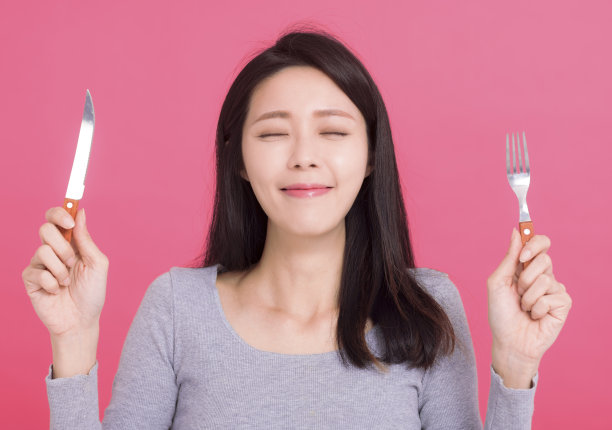 快乐的年轻女子拿着刀叉，等待着美味的饭菜图片下载
