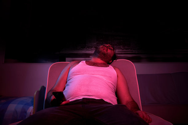 一个40岁的没刮胡子的超重男子看电视，表现出各种情绪，睡觉。懒惰的中年男人图片下载