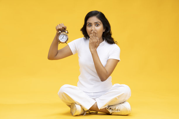 穿着休闲衣服的女人拿着闹钟，库存照片图片下载