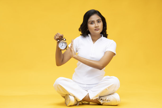 穿着休闲衣服的女人拿着闹钟，库存照片图片下载