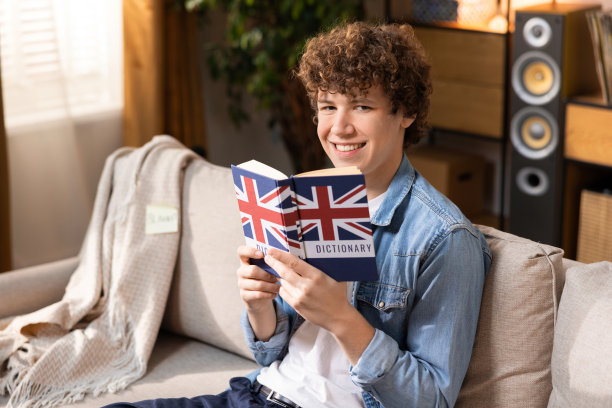 快乐的青少年在平静中学习英语。他高兴地从字典上抬起头，微笑着。他正在准备上大学图片下载