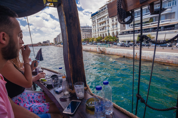 侧视图照片，一个年轻人坐在一个船酒吧，看着美丽的大海图片下载