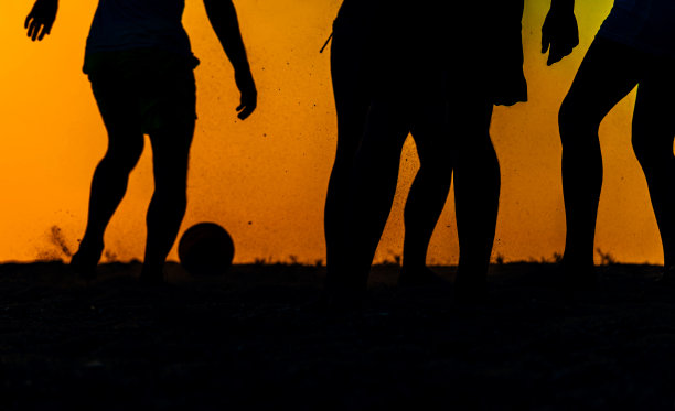 朋友们在沙滩上一起踢足球图片下载