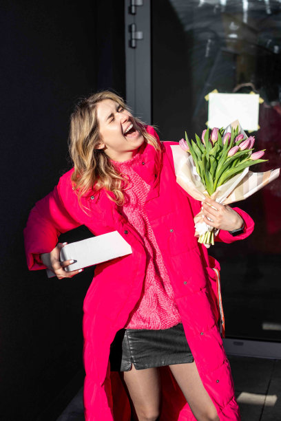 垂落的画像，得意的笑着的金发女人带着礼物，花束粉红的郁金香图片下载