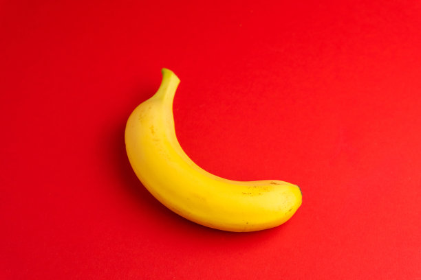 黄色香蕉在红色孤立背景。健康的减肥食品。热带新鲜水果饮食概念图片下载