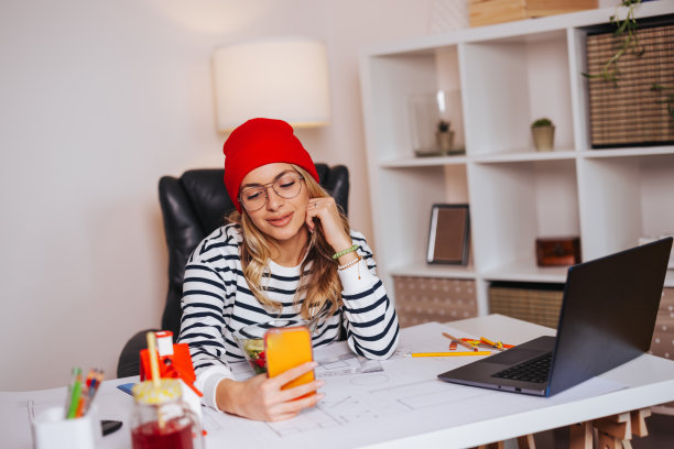 美丽的年轻女子在她的现代家庭办公室用手机自拍图片下载