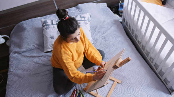 一个孕妇在她的卧室里画画。图片下载
