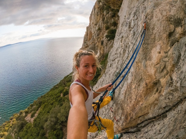 登山者在岩壁上自拍，欣赏海景图片下载