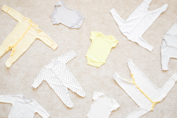 浅地毯背景上不同的新生儿紧身衣。婴儿衣服。自顶向下的观点。图片下载