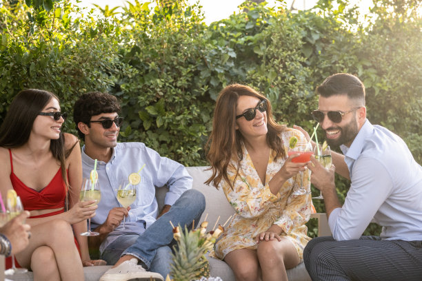 现场的人们微笑着，喝着鸡尾酒，愉快地敬酒，优雅的户外聚会，一个小型企业的团队合作图片下载
