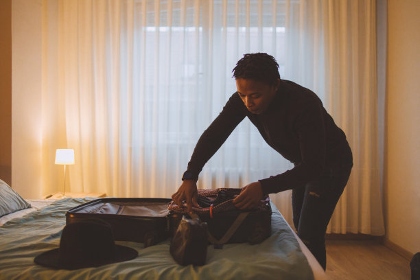 一位年轻的非裔美国男子正在收拾行李准备旅行图片下载