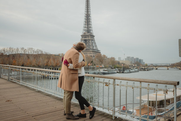 在巴黎埃菲尔铁塔前的一座桥上，一对男女紧紧拥抱在一起图片下载