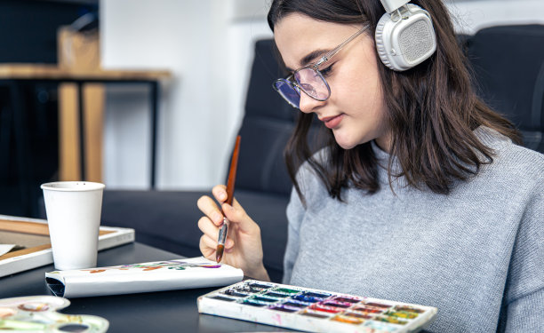 一位时髦的年轻女子在家里用颜料画画。图片下载