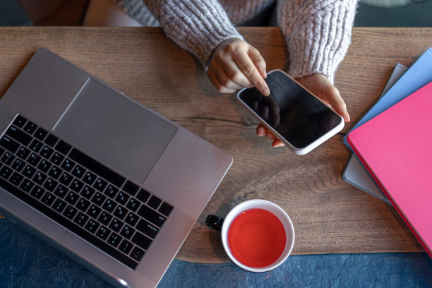 在咖啡馆里用笔记本电脑工作的女人喝着茶，俯视图。图片下载