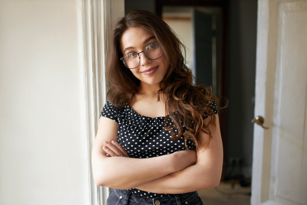 社交距离、家庭生活、人和生活方式概念。可爱时尚的十几岁女孩，胖嘟嘟的脸颊，戴着眼镜在室内摆姿势，双臂交叉放在胸前，微笑着看着镜头图片下载