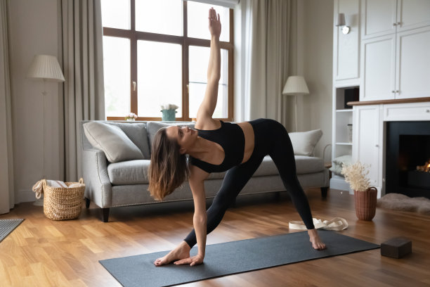 年轻美丽的运动妇女练习瑜伽做Utthita Trikonasana图片下载