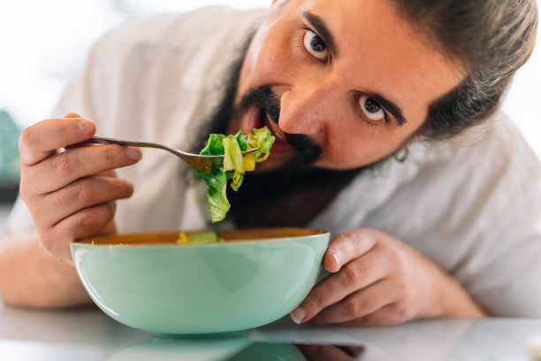 一个留着胡子的年轻人吃沙拉的特写图片下载